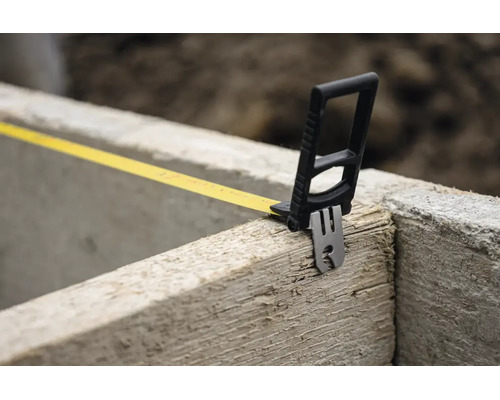 Rollbandmaß mit speziellem Endhaken an einer Holzkante auf einer Baustelle.