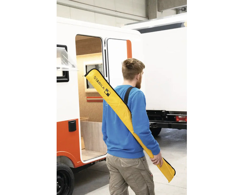 Mann mit einer Stabila Tragetasche für Wasserwaagen über der Schulter neben einem Fahrzeug.