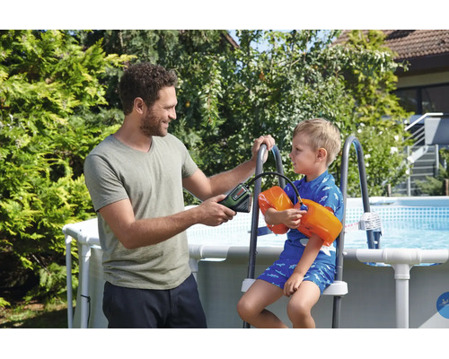 Mann pumpt Schwimmflügel eines Kindes mit einer Akku-Luftpumpe an einem Gartenpool auf.