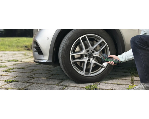 Eine Person pumpt mit der Bosch Akku-Druckluftpumpe EasyPump einen Autoreifen im Außenbereich auf.