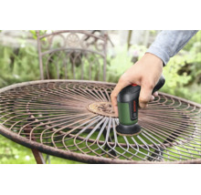 Eine Person benutzt eine Bosch Reinigungsbürste, um Rost von einem runden Metall-Gartentisch zu entfernen.