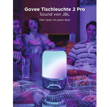 Govee Tischleuchte 2 Pro mit JBL Sound in einem Wohnzimmer mit Personen, farbiger Beleuchtung und Snacks.