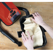 Einsetzen eines Papier-Schmutzfangbeutels in einen Einhell 18 Volt Power X-Change Nass-Trockensauger auf einer Werkbank.