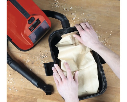 Einsetzen eines Papier-Schmutzfangbeutels in einen Einhell 18 Volt Power X-Change Nass-Trockensauger auf einer Werkbank.