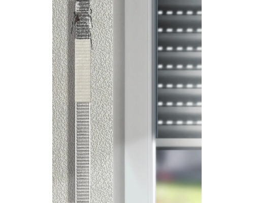 Reparaturset für Rollladengurt an einer verputzten Wand neben einem Fenster.