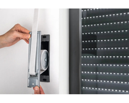Einbau eines Gurtwicklers für Rollläden in die Wand neben einem Fenster mit geschlossenem Rollladen.