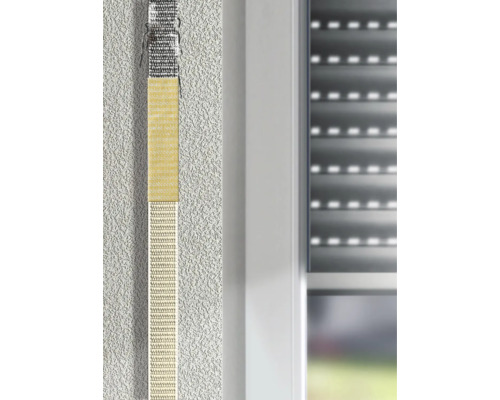 Rollladengurt-Reparaturset an einem Gurtband neben einem Fensterrahmen auf einer verputzten Wand.