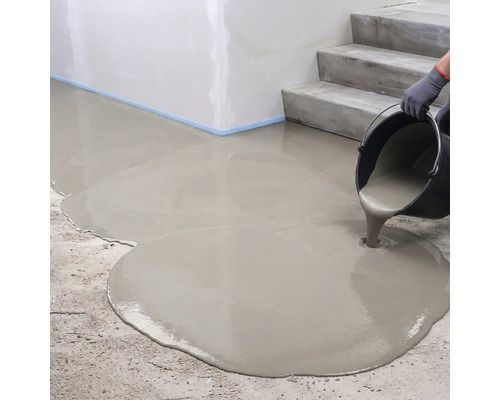 Ausgießen von flüssiger Bodenausgleichsmasse aus einem Eimer auf einen Betonboden neben einer Treppe.