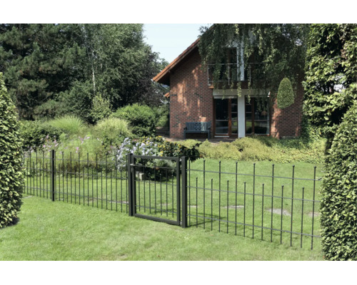 Schwarzer Metallzaun mit passendem Gartentor auf einem grünen Rasen vor einem Backsteinhaus und einem dichten Garten.
