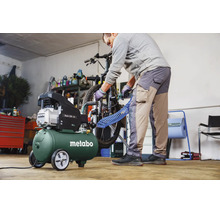 Ein Mann benutzt einen Metabo Basic 200-24 Kompressor in einer hellen Werkstatt, um einen Fahrradreifen aufzupumpen.