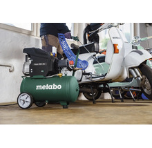 Metabo Basic 200-24 Kompressor mit Spiralschlauch bei der Reinigung eines Motorrollers in einer hellen Werkstatt.