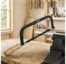 Pattfield Metallsäge mit Holzgriff beim Sägen eines in einem Schraubstock eingespannten Metallrohrs auf einer Werkbank in einer hellen Werkstatt.