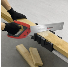 Eine Person schneidet ein Holzbrett mit einer Pattfield Handsäge in einer Gehrungslade.