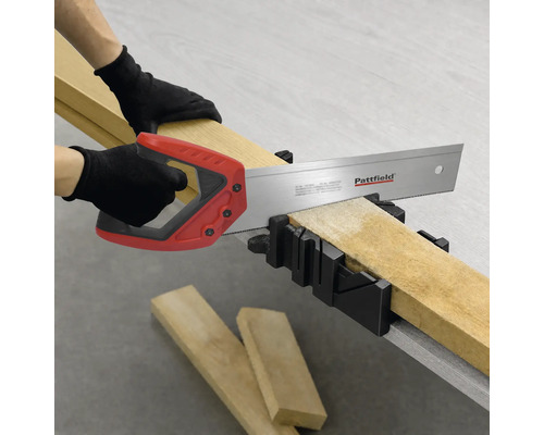 Eine Person schneidet ein Holzbrett mit einer Pattfield Handsäge in einer Gehrungslade.