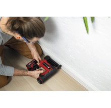 Einhell Akku-Nagler beim Befestigen einer weißen Fußleiste an einer weißen Wand auf hellem Holzboden.
