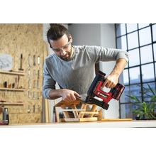 Mann in einer hellen Werkstatt befestigt mit einem Einhell Akku-Nagler Schindeln an einem Vogelhaus aus Holz.