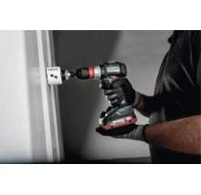 Person benutzt eine Metabo Akku-Bohrmaschine mit Lochsäge zum Bohren eines Loches in eine Wand.