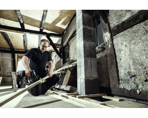 Handwerker schneidet eine Holzleiste mit einer Säbelsäge bei der Sanierung eines Dachstuhls.