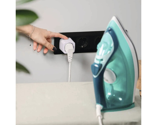 Hand bedient Smart Home Zwischenstecker in Wandsteckdose, Bügeleisen auf Bügelbrett daneben.