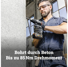 Ein Mann bohrt mit einem Worx Akku-Schlagbohrschrauber mit bis zu 85 Newtonmetern Drehmoment in eine Betonwand.