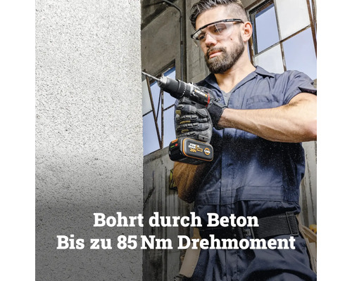 Ein Mann bohrt mit einem Worx Akku-Schlagbohrschrauber mit bis zu 85 Newtonmetern Drehmoment in eine Betonwand.