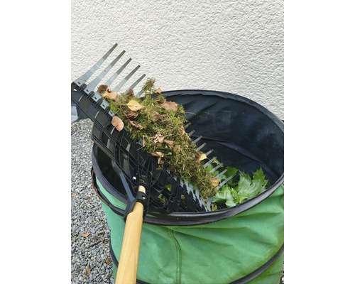 Gartenrechen mit gesammeltem Laub über einem Gartensack