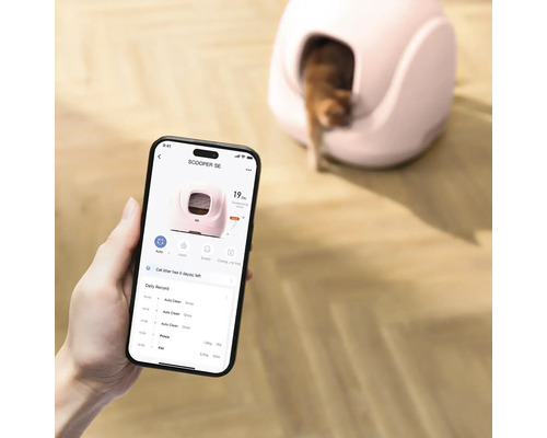 Smartphone-Applikation zur Steuerung einer selbstreinigenden Katzentoilette, im Hintergrund das Gerät mit einer Katze auf Holzboden.