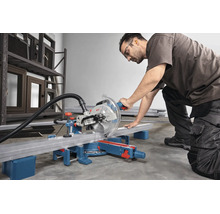 Handwerker mit Schutzbrille und Gehörschutz schneidet ein Metallprofil mit einer Bosch Kapp- und Gehrungssäge in einer Werkstatt.