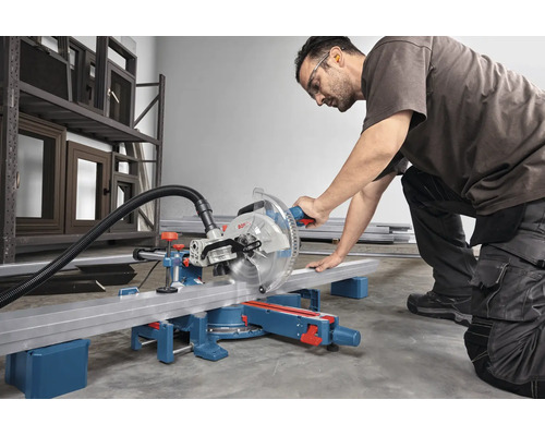 Handwerker mit Schutzbrille und Gehörschutz schneidet ein Metallprofil mit einer Bosch Kapp- und Gehrungssäge in einer Werkstatt.