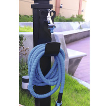 Schwarze Gartenzapfstelle mit silbernem Wasserhahn und einem aufgerollten blauen Gartenschlauch an einer Halterung im Außenbereich.