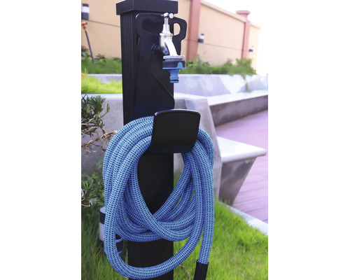 Wasserzapfstelle für den Garten mit flexiblem Gartenschlauch und Wasserhahn an einer schwarzen Säule.