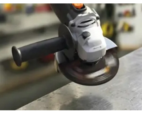 Winkelschleifer mit rotierender Trennscheibe bei der Bearbeitung einer Metallkante in einer Werkstatt.