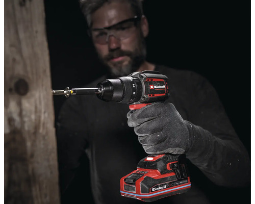 Ein Mann schraubt mit einem Einhell Akku-Schlagbohrschrauber eine Schraube in einen Holzbalken.