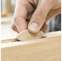 Hand setzt einen Flachdübel aus Holz zur Holzverbindung in eine Nut ein.