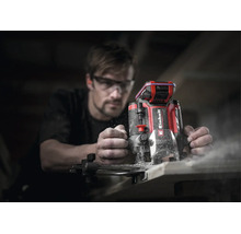 Einhell Akku-Oberfräse bei der Holzbearbeitung durch eine Person mit Schutzbrille in einer Werkstatt.