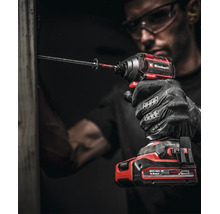 Handwerker mit Schutzbrille und Handschuhen nutzt einen Einhell Akku-Schlagschrauber zum Eindrehen einer langen Schraube in einen Holzbalken.