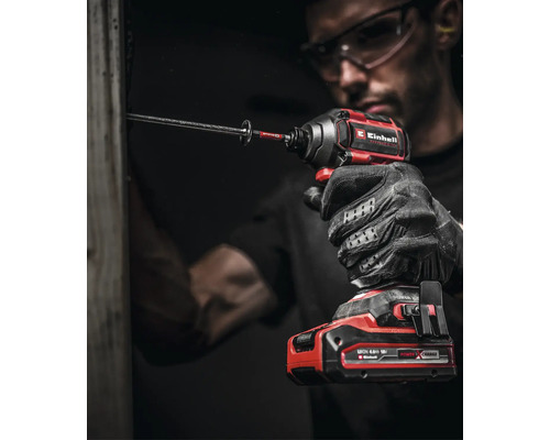 Handwerker mit Schutzbrille und Handschuhen nutzt einen Einhell Akku-Schlagschrauber zum Eindrehen einer langen Schraube in einen Holzbalken.