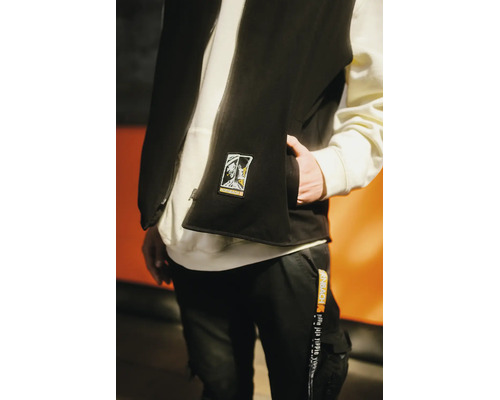 Person trägt eine schwarze Weste mit Hornbach Aufnäher, einen weißen Kapuzenpullover und eine schwarze Arbeitshose mit Hornbach Band.
