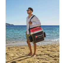 Ein Mann trägt eine Einhell Kühltasche mit Schultergurt und Seitentaschen an einem hellen Sandstrand am Meer. Einhell Logo.