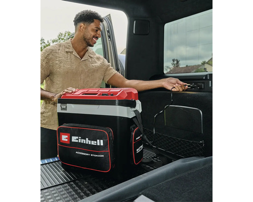 Tragbare Einhell Kühlbox mit Zubehörtasche, die im Kofferraum eines Autos an eine 12-Volt-Steckdose angeschlossen wird.