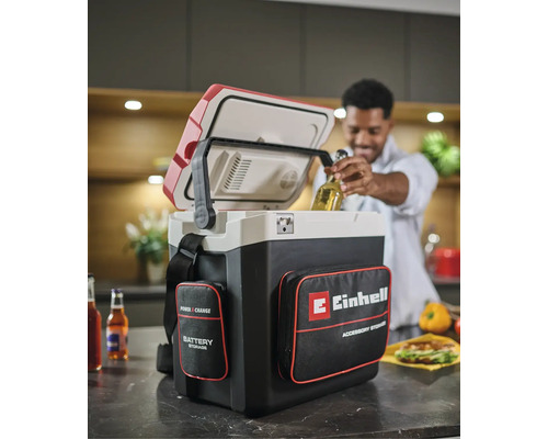 Einhell Power X-Change Akku-Kühlbox mit Zubehörtaschen in einer Küche, ein Mann entnimmt eine Getränkeflasche aus der geöffneten Box.