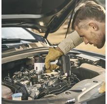 Ein Mann verwendet einen Litheli Akku-Schlagschrauber zur Arbeit an einem Automotor bei geöffneter Motorhaube.