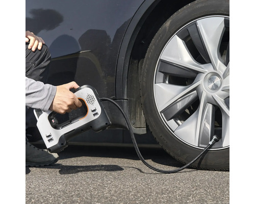 Eine Person verwendet einen tragbaren elektrischen Luftkompressor, um einen Autoreifen aufzupumpen.