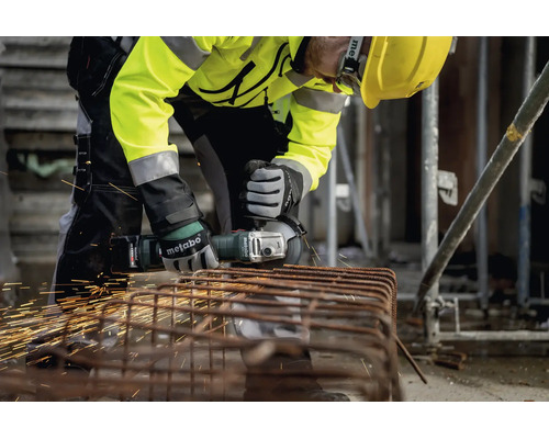 Handwerker mit Metabo Akku-Winkelschleifer schneidet Metallbewehrung auf einer Baustelle, Funkenflug, Sicherheitsausrüstung.