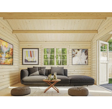 Innenansicht eines Gartenhauses aus Holz mit Sofa, Holztisch, Bodenkissen und Fenster mit Blick ins Grüne.