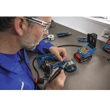 Handwerker lötet mit einem Bosch Akku Lötkolben an einem geöffneten Elektrowerkzeug an einem Werkstatttisch.