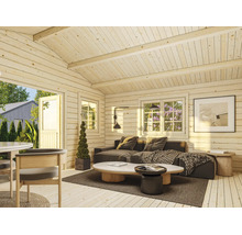 Heller Innenraum eines Gartenhauses aus Holzbohlen mit Sofa, Couchtischen und großen Fenstern.