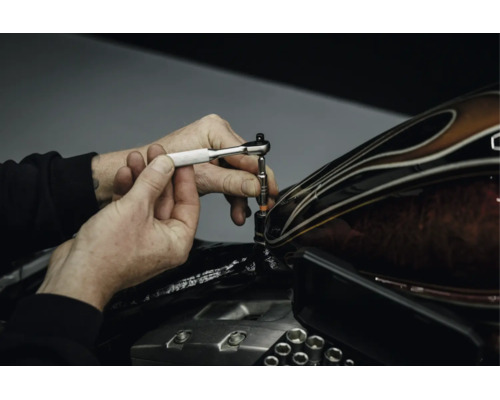 Eine Hand nutzt eine Mini-Umschaltknarre für Arbeiten an einem Motorrad.