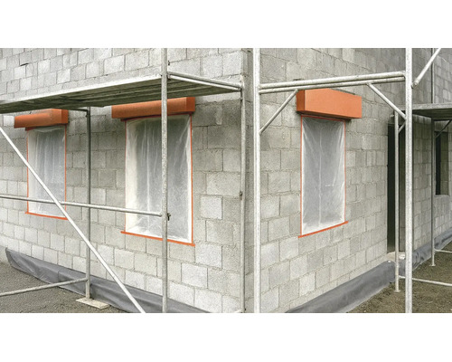 Rohbau aus Betonsteinen mit Gerüst, Fensteröffnungen mit Schutzfolie und Rollladenkästen auf einer Baustelle.