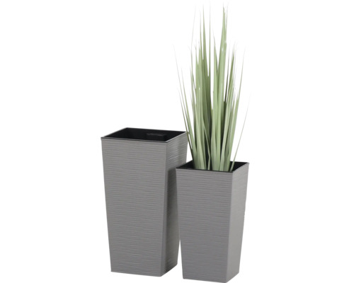 Zwei hohe, graue, quadratische Pflanzkübel mit horizontal gerillter Oberfläche, einer davon mit Kunstgras bepflanzt.